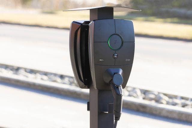 En Zaptec Pro laddbox monterad på en stolpe utomhus vid en parkering.